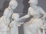 two figurines of a woman and a child sitting on a bench