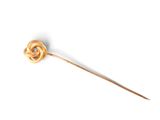 a gold pin with a knot on it on a white surface
