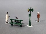 toy figurines of a man and a woman on a bench next to a traffic light