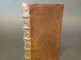 an old book with a brown leather cover sitting on top of a table