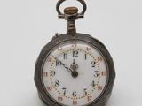 a small silver pocket watch on a white surface