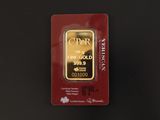 un lingot d'or dans un emballage rouge posé sur une surface noire