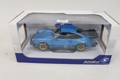 La petite voiture bleue se trouve dans la boîte posée sur la table.