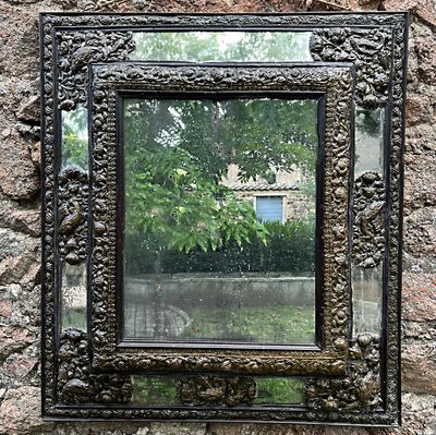 un miroir accroché à un mur de pierre, avec un arbre en arrière-plan