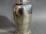 a silver vase sitting on a table with a silver lid