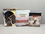 Trois livres sont posés sur une table, avec un chien devant eux.