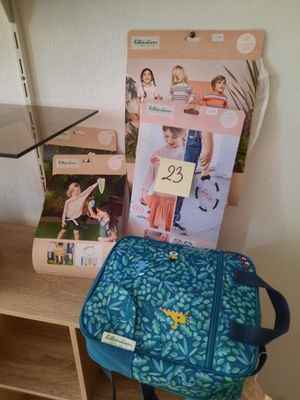 un sac à dos bleu posé sur une étagère en bois à côté d'une bibliothèque