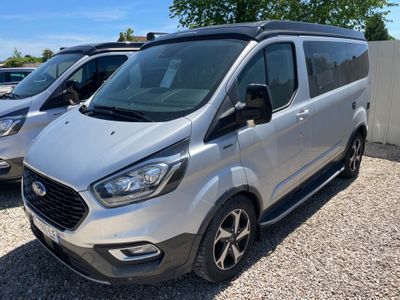 La camionnette argentée est garée à côté d'autres camionnettes sur un parking.