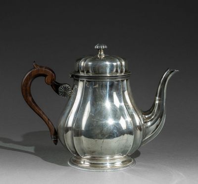 une théière ancienne en argent, munie d'une poignée en bois, posée sur une table