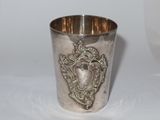 a silver cup sitting on a table with a silver handle