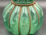 a green vase with a rope around it on a table