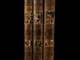 two old books are stacked on top of each other on a black background