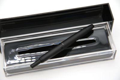 un stylo dans une boîte transparente posée sur une surface blanche