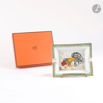 un petit plateau orné d'un coq, posé à côté d'une boîte orange
