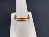 un gros plan d'une bague en or posée sur un présentoir à bagues blanc