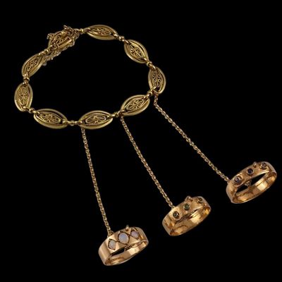 un collier en or composé de trois anneaux et d'une chaîne, sur fond noir