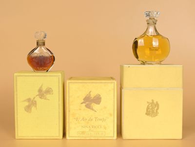 two bottles of perfume sitting on top of boxes next to each other