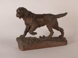 statue d'un chien en train de courir, posée sur un socle en bois, sur fond blanc