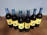 six bottles of wine are lined up on a wooden table