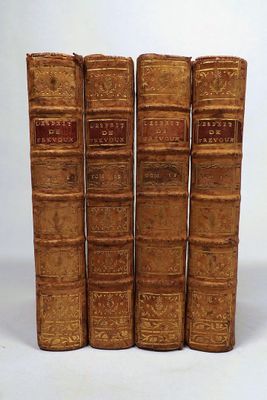 four old books are lined up in a row on a white surface