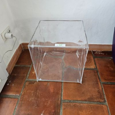 une boîte transparente posée par terre près d'un mur