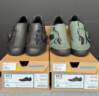trois paires de chaussures Shimano posées sur des cartons