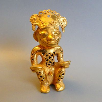 a gold figurine of a man with a bird in his hand