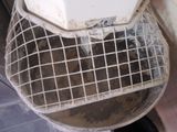 a dirty toilet with a metal basket on top of it