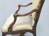 an old chair with a beige upholstered seat and a wooden frame