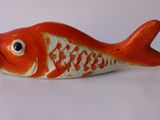 une figurine de poisson rouge et blanche posée sur une surface blanche