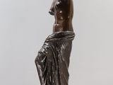 bronze statue of a woman sitting on a marble pedestal