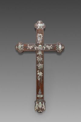 une vieille croix en bois ornée de fleurs, sur fond gris