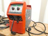 an orange and black welding machine sitting on top of a wooden table