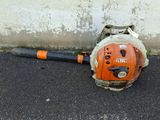 a small blower sitting on the ground next to a concrete wall