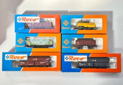 six boîtes contenant des trains miniatures posées sur une surface blanche