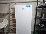 a white refrigerator in a room with shelves and a chair