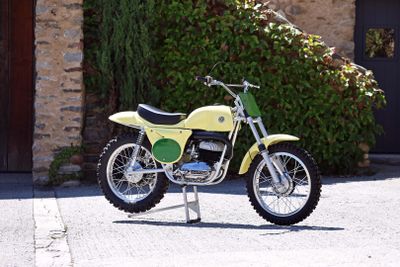une moto tout-terrain jaune garée devant un bâtiment en pierre