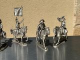 three figurines of men riding horses and holding flags