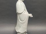 statue of a woman in a white robe standing on a rock