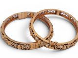 two gold bracelets with diamonds on them on a white surface