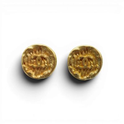 une paire de boucles d'oreilles en or sur une surface blanche