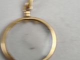 a gold pendant with a magnifying glass in it