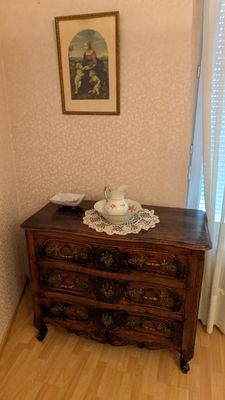 une commode dans un coin d'une pièce, avec un tableau accroché au mur