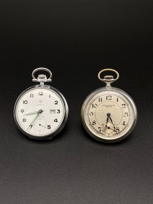deux montres de poche en argent posées l'une à côté de l'autre sur une surface noire