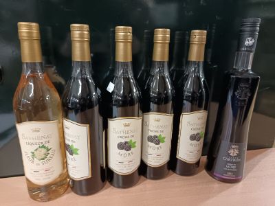 Des bouteilles de vin sont alignées sur un comptoir devant un tableau noir