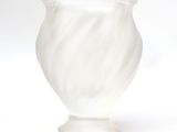 a white glass vase with a swirly design on it