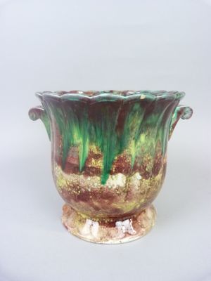 a green and brown vase sitting on a white surface