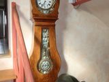 a grandfather clock in the corner of a room next to a couch