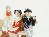 two figurines of people sitting on a bench