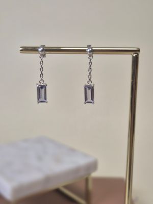 silver earrings on a gold stand with a white square